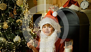 Kid Santa Claus enjoying in served gingerbread cake and milk. Santa Claus eating cookies and drinking milk on Christmas