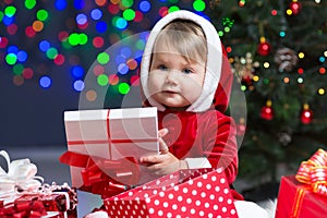 Kid Santa Claus near Christmas tree with gifts