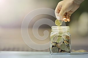 Kid saving coin in glass piggy bank