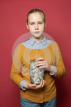 Kid with saving money in glass jar