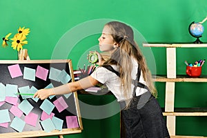 Kid and school supplies on green wall background