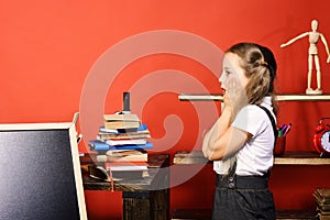 Kid and school supplies on red wall background