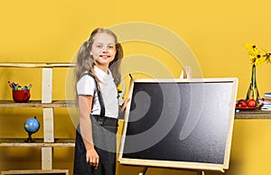 Kid and school supplies on yellow wall background