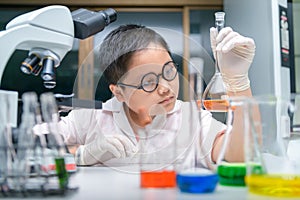 Kid scientist making experiment in chemical laboratory photo