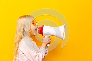 Kid shouting through megaphone. Communication concept. yellow background as copy space for your text