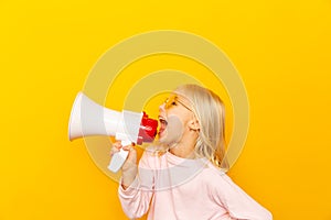 Kid shouting through megaphone. Communication concept. yellow background as copy space for your text