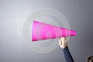 Kid shouting through pink paper megaphone.