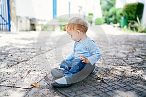 Kid sits on a metal hatch in the yard, turning sideways