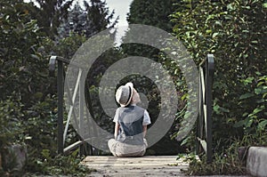 Kid sitting alone on a stairs in th garden