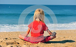 Kid sitting at the sea on sand beach