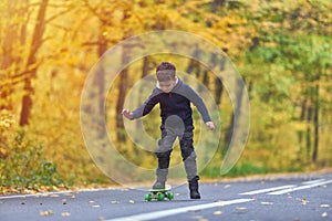 Kid skateboarder doing skateboard tricks in autumn environment