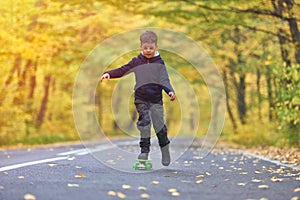 Kid skateboarder doing skateboard tricks in autumn environment