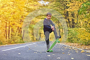 Kid skateboarder doing skateboard tricks in autumn environment