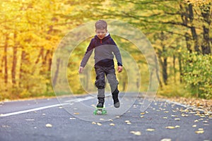 Kid skateboarder doing skateboard tricks in autumn environment