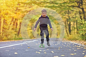 Kid skateboarder doing skateboard tricks in autumn environment