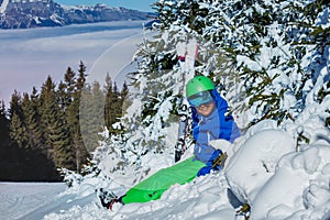 Kid with ski helmet and googles hold skies smile sit in snow