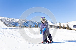 Kid in ski mask skiing on snow downhill