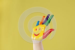 Kid with smiling face drawn on palm against background, closeup