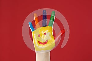 Kid with smiling face drawn on palm against background, closeup