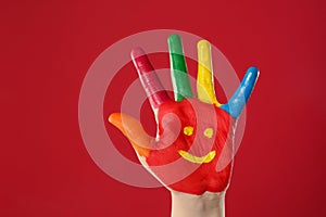 Kid with smiling face drawn on palm against background, closeup