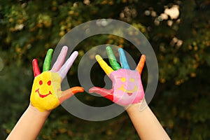 Kid with smiling face drawn on palms in park, closeup