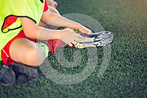Kid soccer player is sitting and catch the soles of the feet because of pain