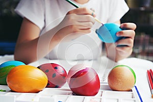 Kid spending holiday to painting fancy easter eggs