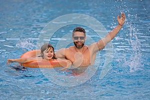 Kid splash water in pool. Father and son swimming and splashing in blue sea water. Family on summer holiday. Happy