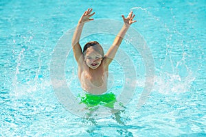 Kid splashing in summer water pool. Kid splash in swim pool. Excited happy little boy jumping in pool, water fun. Kid