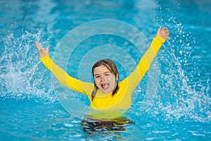 Kid splashing in summer water pool. Kid splash in swim pool. Excited happy little boy jumping in pool, water fun. Kid