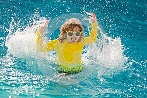 Kid splashing water in pool. Little kid splashing in blue water of swimming pool. Cute child swimming and splashing