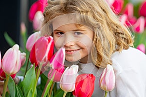 Kid in spring tulips blossom park. Happy childhood. Spring holidays. Adorable kid smelling tulips in spring garden. Cute