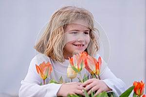 Kid in spring tulips blossom park. Happy childhood. Spring holidays. Adorable kid smelling tulips in spring garden. Cute