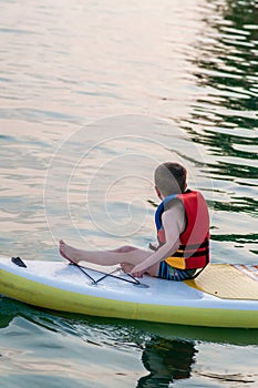 Kid and stand-up paddle board together.