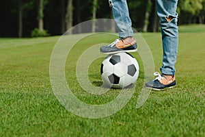 Kid standing with soccer ball on green meadow