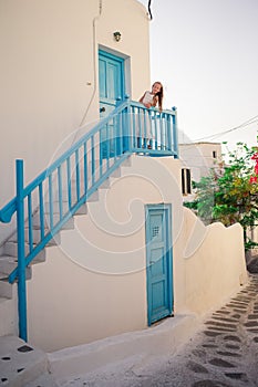 Kid at street of typical greek traditional village with white walls and colorful doors on Mykonos Island