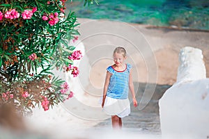 Kid at street of typical greek traditional village with white walls and colorful doors on Mykonos Island, in Greece