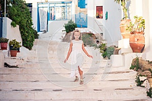 Kid at street of typical greek traditional village with white walls and colorful doors on Mykonos Island