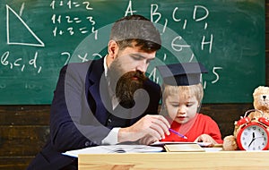 Kid studies individually with teacher, at home. Individual schooling concept. Teacher and pupil in mortarboard