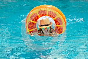 Kid swim with floating ring in swimming pool. Kids summer vacation. Happy child boy with inflatable ring in poolside