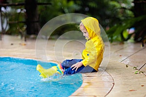 Kid in swimming pool in rain. Tropical storm
