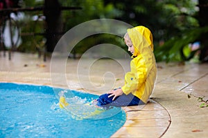 Kid in swimming pool in rain. Tropical storm