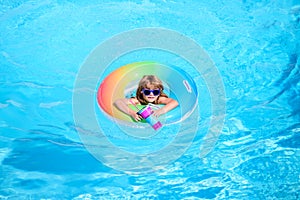 Kid in swimming pool, relax swim on inflatable ring and has fun in water on summer vacation, blue water background, copy