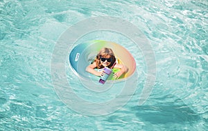 Kid in swimming pool, relax swim on inflatable ring in water on summer vacation.