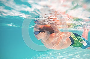 Kid swimming in pool underwater. Child boy swim underwater in sea. Child playing and diving in swimming pool. Funny kids