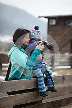 Kid taking a photo with mother holding him in arms