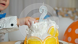 Kid tasting the birthday cake with the number 2 on the cake. Hand close-up