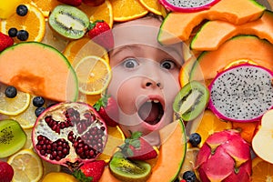 Kid tasting fruits. Excited kids face with mix of strawberry, blueberry, strawberry, kiwi, dragon fruit, pomegranate