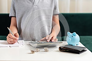 Kid teen boy counting money and taking notes, saving money in a piggy bank. Learning financial responsibility and