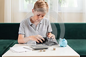 Kid teen boy counting money and taking notes, saving money in a piggy bank. Learning financial responsibility and